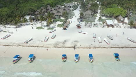 Aerial-top-down-shot-over-luxury-apartments-of-resort-with-boats-in-sandy-beach-and-crystal-clear-water-in-Tulum,Mexico