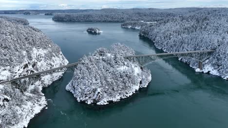 Wide-aerial-shot-pushing-towards-Deception-Pass-bridge-covered-in-snow