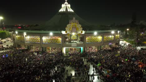 Aerial-view-away-from-the-evening-lit-Basilica-of-Guadalupe,-nighttime-in-Mexico