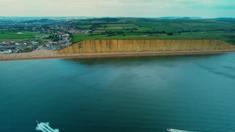 Bridport-West-Bay-cliffs-British-seaside-sandstone-coastline-turquoise-ocean-aerial-wide-orbit-left