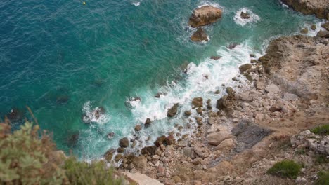 High-angle-video-shot-of-blue-water-hitting-coastal-rocks