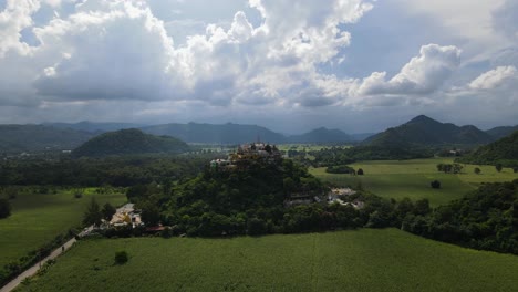 Aerial-ascending-footage-of-this-temple-in-the-middle-of-a-cornfield,-mountains-in-the-horizon,-super-lovely-sky
