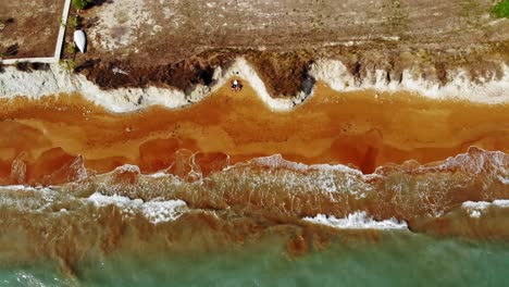 Ocean-Waves-Splashing-On-Red-Sand-Shore-At-Megas-Lakkos-Beach-In-Greece---aerial-top-down