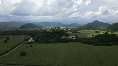Absteigende-Luftaufnahmen,-Die-Diese-Maisfelder-Und-Den-Berühmten-Simalai-songtham-tempel-Mit-Erstaunlichem-Hintergrund-In-Khao-Yai,-Pak-Chong,-Thailand,-Zeigen