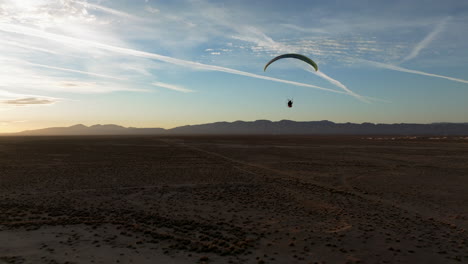 Silhouette-of-a-powered-paraglider-flying-over-the-Mojave-Desert-at-sunset