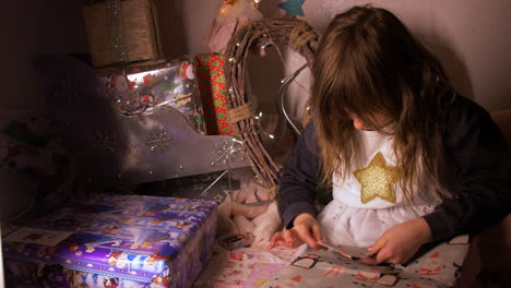 Weite-Aufnahme-Eines-Kleinen-Mädchens,-Das-Geburtstags-weihnachtsgeschenk-In-Einem-Gemütlichen-Haus-Einwickelt