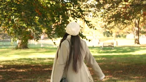 Attractive-girl-looks-and-walks-around-at-the-chilly-fall-autumn-leaves-at-a-city-park