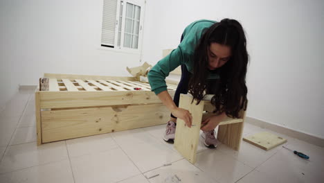 Latino-girl-fixing-wooden-shelf-drawer-at-living-room