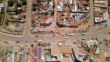 Aerial-of-busy-road-with-motorbikes,-cars-and-trucks-near-slum-town-in-rural-Kenya