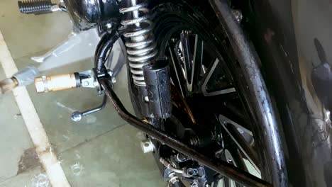 Worker-washing-motorcycle-with-pressurized-water-jet,-at-washing-center