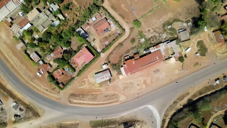 Top-down-aerial-of-motorcyclist-driving-over-road-in-a-small-town-in-Kenya