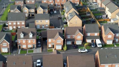 Property-ladder-new-British-housing-estate-aerial-view-overlooking-rooftops-Birdseye-dolly-left