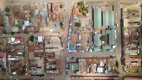 Top-down-aerial-of-small,-busy-streets-in-a-Kenyan-town---drone-flying-backwards-over-neighborhoods