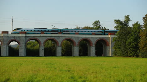 Slow-motion-railway-viaduct-with-a-passing-passenger-train-crossing-the-bridge