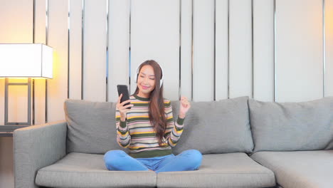 Asiatische-Frau,-Die-Online-streaming-musik-Mit-Smartphone-Und-Kopfhörern-In-Der-Privatsphäre-Des-Familienhauses-Hört,-Vollbild