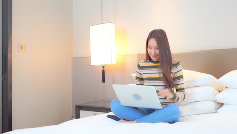 Young-Asian-Woman-Working-From-Home-or-Writing-Novel-Using-Laptop-Computer-in-Privacy-of-Bedroom,-Full-Frame