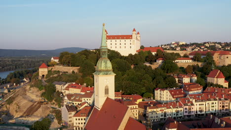 Wide-cinematic-drone-shot-with-the-Saint-Martin's-Cathedral-in-the-foreground-and-the-Bratislava-Castle-in-the-background-in-Bratislava-Slovakia