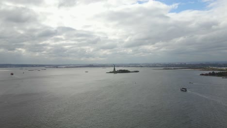 Aerial-view-of-ferries-driving-towards-the-statue-of-Liberty,-in-New-York,-USA---tracking,-drone-shot