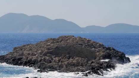 Small-rock-island-by-Jerusalem-Beach-in-Kafelonia-with-mountains-in-background