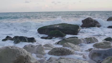 4K-Slow-motion-cinematic-shot-of-big-waves-hitting-rocks-on-a-beach,-at-Church-Ope,-Portland-Dorset,-in-England,-during-sunset
