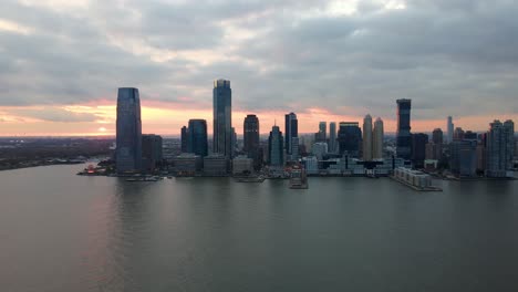 Aerial-view-of-the-waterfront-of-the-Jersey-city,-colorful-dusk-sky-in-New-York,-USA---tracking,-drone-shot
