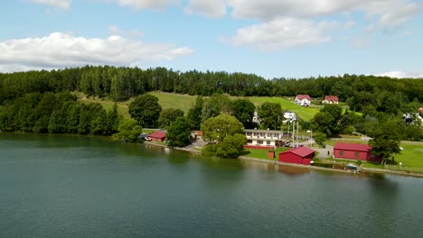 Aerial-backwards-shot-of-beautiful-idyllic-lake-with-forest-trees-and-weather-station-or-meteorological-office-in-Poland---4K-Drone