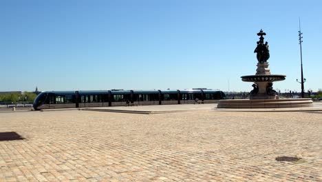 Platz-Der-Place-De-La-Bourse-Mit-Trolley,-Der-Während-Der-Covid-19-Pandemie-Davor-Angehalten-Wurde,-Mit-Wenigen-Menschen-Und-Ausgeschaltetem-Brunnen,-Schwenk-Nach-Links,-Enthüllungsaufnahme