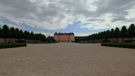 Timelapse-of-beautiful-castle-with-people-walking-on-palace-garden-on-cloudy-day,-Schwetzingen-Germany