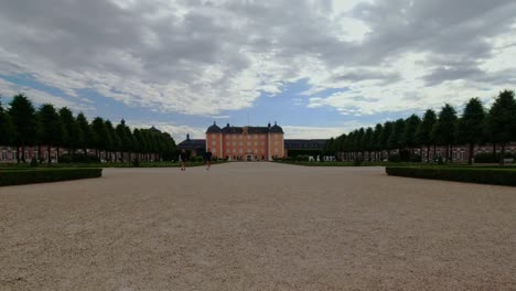 Zeitraffer-Des-Schönen-Schlosses-Mit-Menschen,-Die-An-Bewölkten-Tagen-Im-Schlossgarten-Spazieren-Gehen,-Schwetzingen-Deutschland