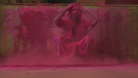 A-man-stooping-down-covered-in-pink-powder