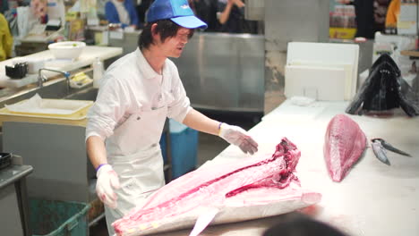 Carnicero-De-Pescado-Diseccionando-Atún-De-Pescado-Grande-Frente-A-La-Audiencia-En-El-Mercado-De-Pescado-De-Toretore-Ichiba-En-Wakayama,-Japón---Tiro-Medio