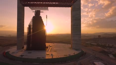 Drone-flying-through-'Manto-de-María'-monument,-against-and-amazing-sunset-during-the-golden-hour-with-sun-flares,-in-Barquisimeto,-Venezuela