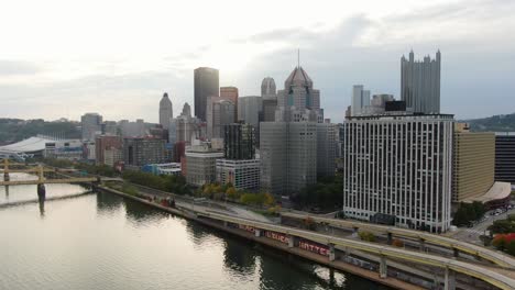 Dramatic-aerial-pullback-reveals-Fort-Duquesne-Bridge-over-Allegheny-River-with-sunshine-reflecting-on-downtown-Pittsburgh-PA-skyscrapers