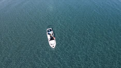 A-White-Boat-Floating-On-The-Shallow-Clear-Blue-Water-In-Argentina-On-A-Summer-Day---aerial-drone
