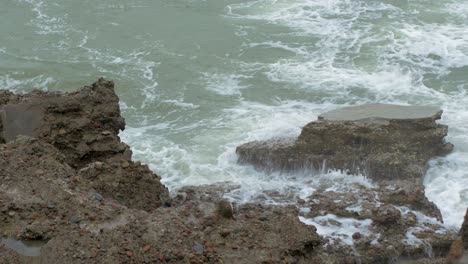 Big-stormy-waves-breaking-against-abandoned-seaside-fortification-building-ruins-at-Karosta-Northern-Forts-in-Liepaja,-Baltic-sea-coastline,-wave-splash,-overcast-day,-medium-angle-closeup-shot