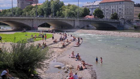 Summer-in-Munich,-Germany,-People-Sunbathing-on-Isar-River-at-Reichenbach-Bridge