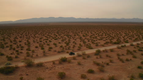Ein-Jeep-Mit-Allradantrieb-Auf-Einer-Unbefestigten-Straße-Bei-Sonnenuntergang-In-Der-Mojave-Wüste---Luftbild