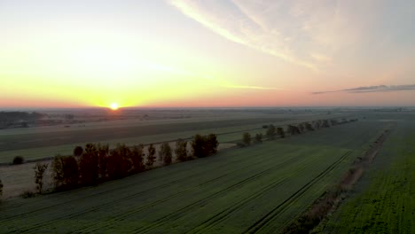 Lebendiger-Sonnenuntergang-Am-Horizont-über-Lettlands-Agrarlandschaft---Absteigende-Luftaufnahme