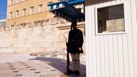 La-Guardia-Presidencial-Griega-Con-Uniforme-Militar-Tradicional,-Evzone,-Se-Está-Preparando-Para-El-Cambio-De-Guardia-Ceremonial-Frente-Al-Parlamento-Helénico,-Mientras-Sostiene-Un-Rifle-Rojo