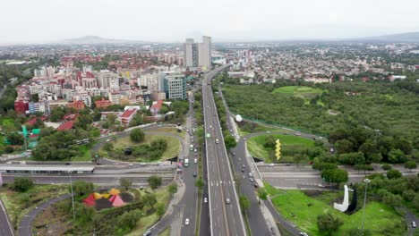 Spectacular-aerial-flight-above-downtown-Mexico-city-freeway-with-vehicular-traffic-traveling-on-freeway,-expressway,-passageway,-intersection,-and-bypass-on-cloudy-day,-overhead-approach-drone