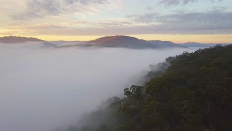 Tal-In-Der-Australischen-Landschaft,-Die-Bei-Sonnenaufgang-Von-Dichtem-Nebel-Mit-Berggipfeln-Und-Bunten-Wolken-Bedeckt-Ist