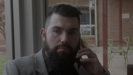 Man-wearing-a-suit-facing-front-on-talking-on-a-mobile-phone