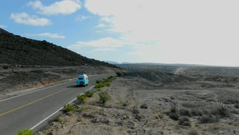 Kamerafahrt-Aus-Der-Luft,-Blauer-Lieferwagen,-Der-Sich-Entlang-Der-Autobahn-Von-La-Purisima-Baja-California-Sur,-Mexiko-Bewegt,-Malerischer-Blick-Auf-Die-Felslandschaft-Und-Die-Berge-Im-Hintergrund