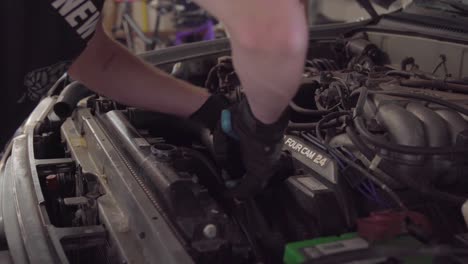 Young-man-auto-mechanic-removes-radiator-hose-from-Toyota-engine-block