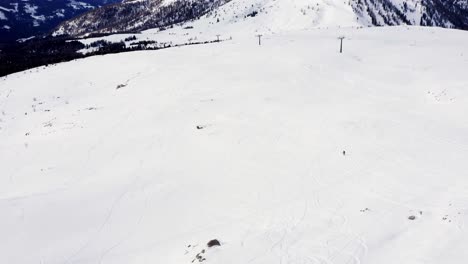 Aerial-view-of-skier-skiing-slowly-down-the-snowy-mountain-during-beautiful-cold-winter-day-during-covid-19-pandemic