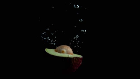 Avocado-Fällt-Ins-Wasser-Super-Slowmotion,-Schwarzer-Hintergrund,-Viele-Luftblasen,-4k240fps