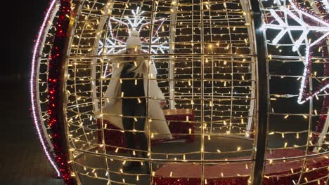 Happy-Woman-in-White-Jacket-Playing-Inside-Christmas-Decoration-of-Lights