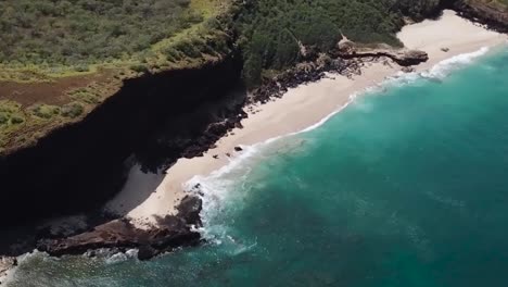 Drone-aerial-rise-cliff-side-beach-blue-water-waves