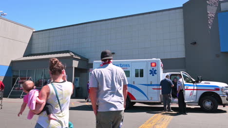 Familia-Con-Mascarilla-Con-Ambulancia-De-Bay-Cities-Frente-A-Coos-Bay-Walmart-Durante-Una-Pandemia-En-Oregon,-Estados-Unidos