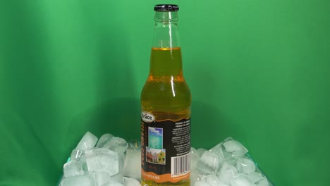 3-3-Botella-De-Vidrio-De-Bebida-De-Champán-Kola-Con-Sabor-A-Marca-Grace-Que-Gira-360-Grados-En-Un-Recipiente-Lleno-De-Hielo-Frente-A-Una-Pantalla-Verde